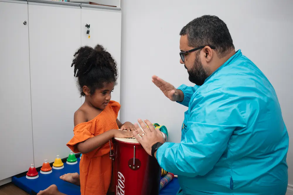 Foto de uma criança tocando um instrumento musical com o terapeuta